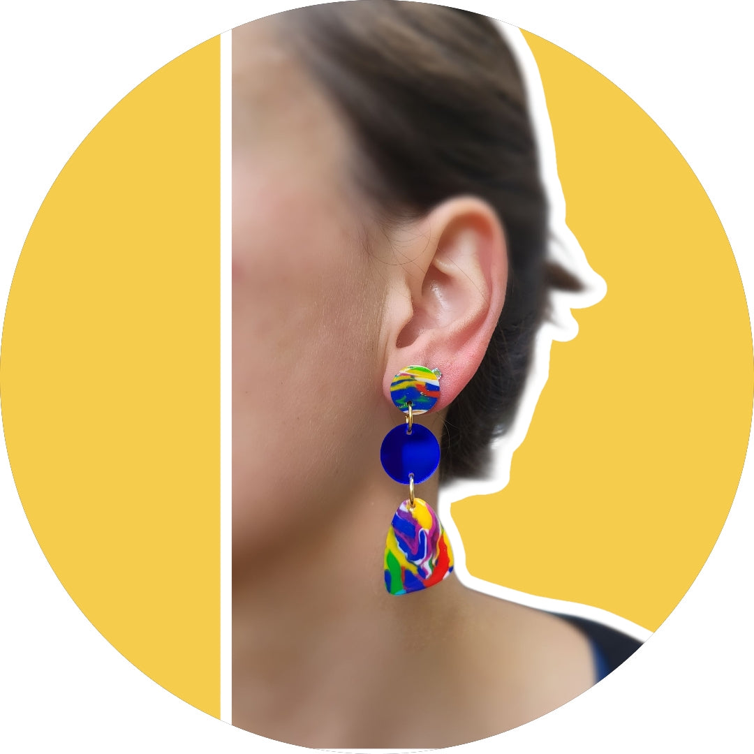 Vibrant statement earrings with, abstract polymer clay pendant with splashes of yellow, pink, and turquoise, these earrings are complemented by a striking cobalt blue hoop and a small circular top piece. Lightweight and eye-catching, they are perfect for adding a pop of color to any outfit. Ideal for those who love artistic, contemporary jewelry.